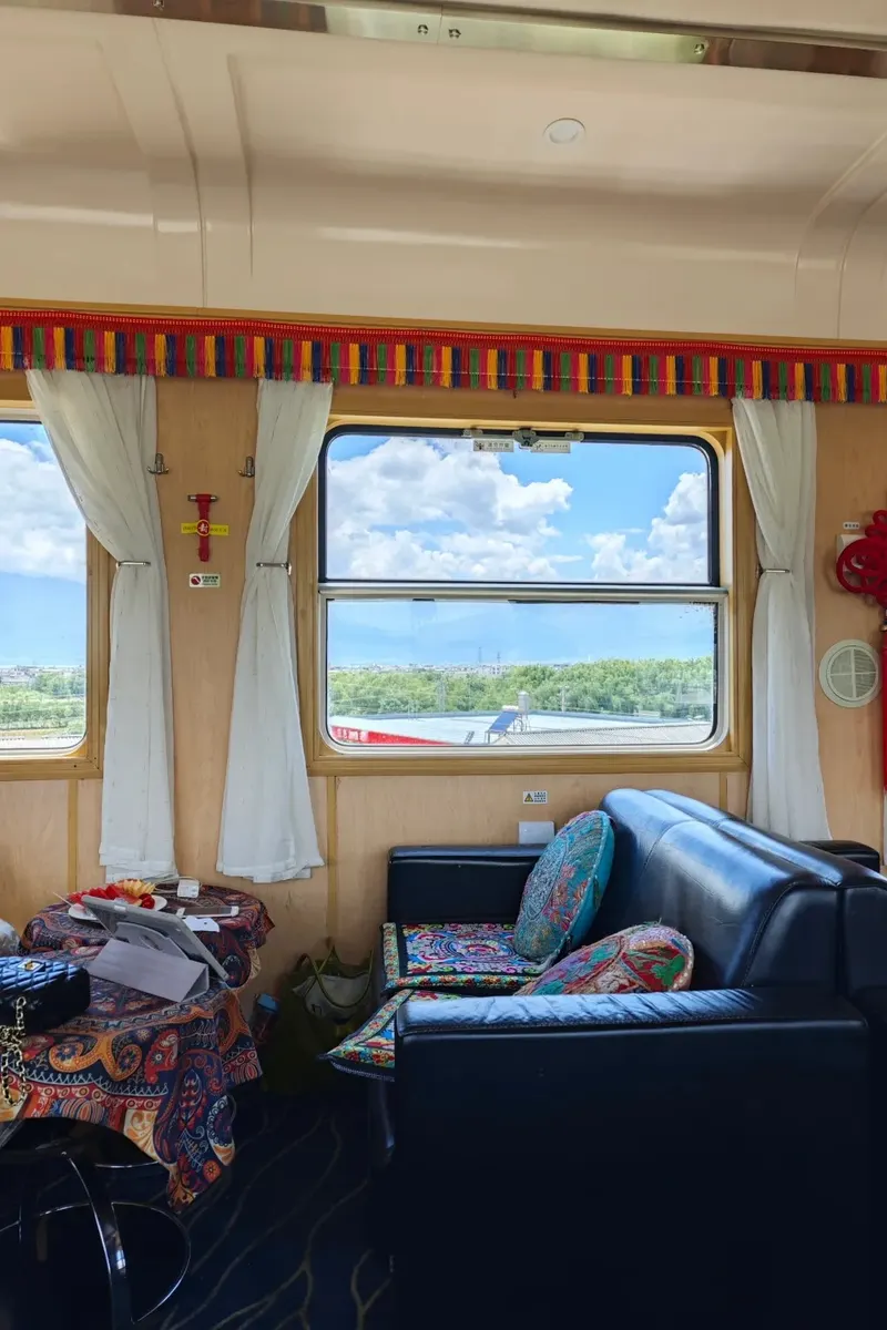 Train cabin looking out at fields and mountains on the Dali–Lijiang hop