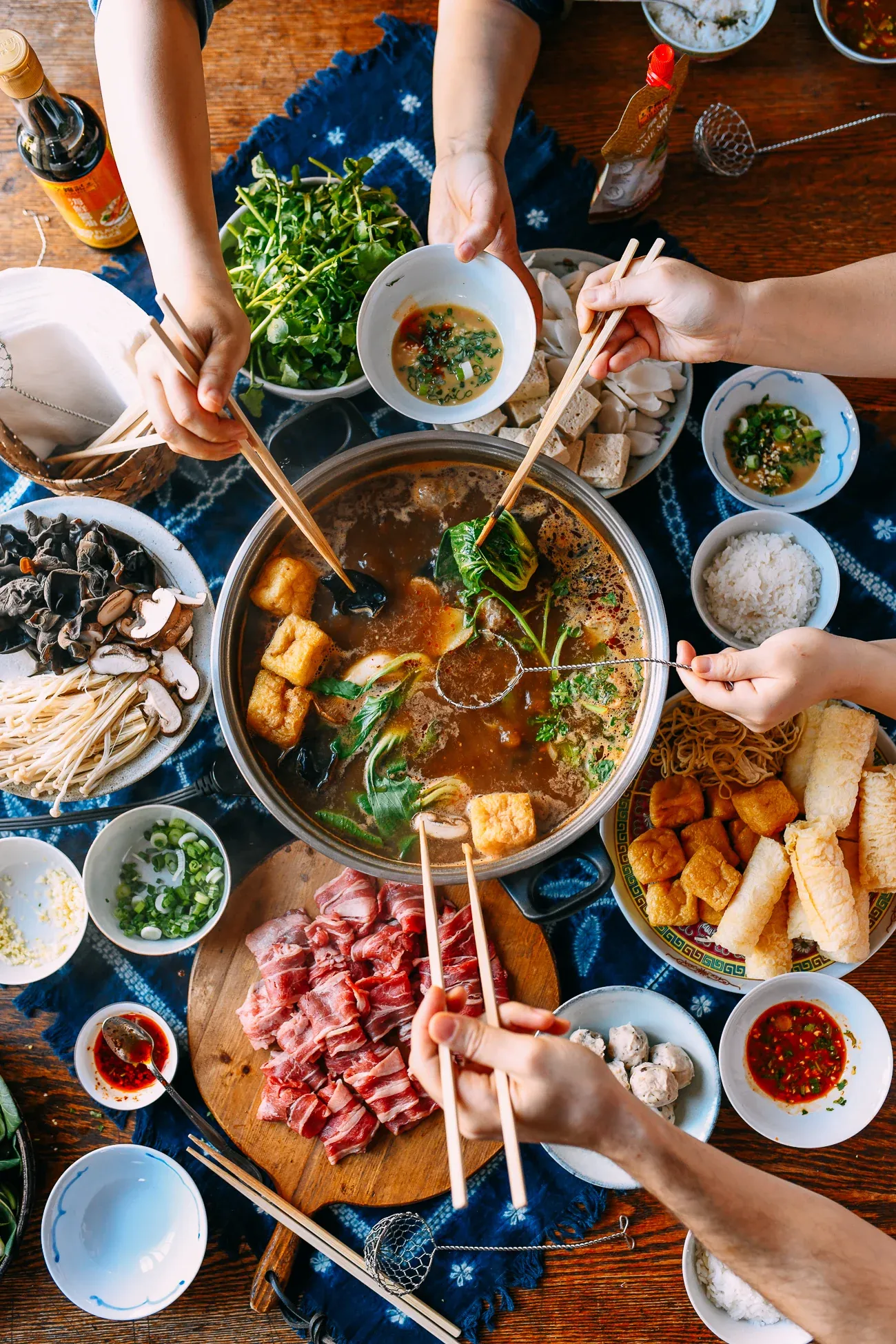 Traditional Chinese hotpot shared meal with multiple dishes and chopsticks on table