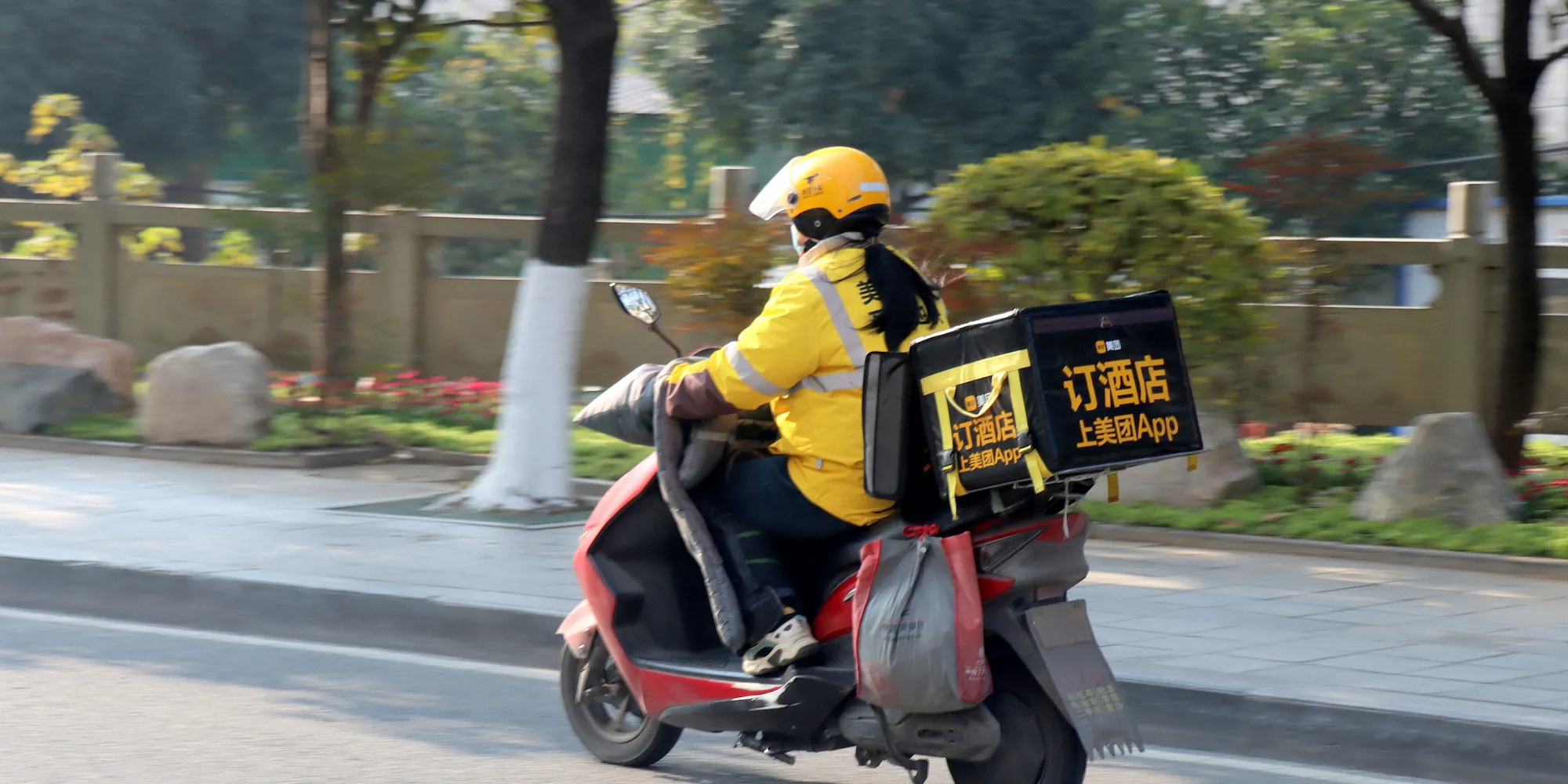 Meituan food delivery rider on scooter with yellow delivery box in Chinese city