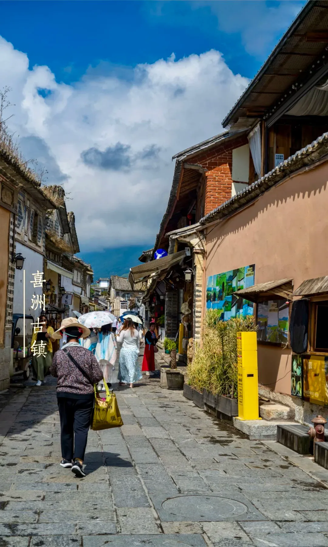 Stone lane in Xizhou Old Town with Bai-style houses and visitors walking
